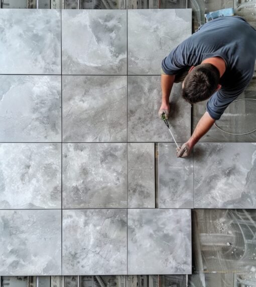 A man working on a tile floor, suitable for construction projects A man working on a tile floor, suitable for construction projects.
