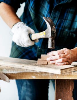 Woman carpenter using hammer pushing nail on a wood